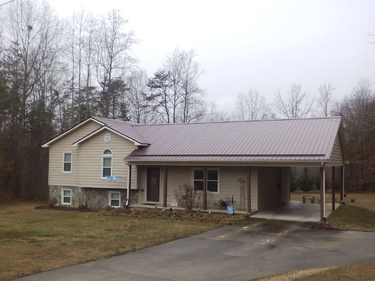 Burgundy metal roof on a tan split level home with an attached carport in Colliersville