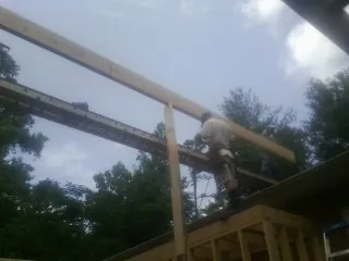 Carpenter setting a ridge beam over a new addition frame — Ice Dam Removal by Roofing Brothers in Colliersville