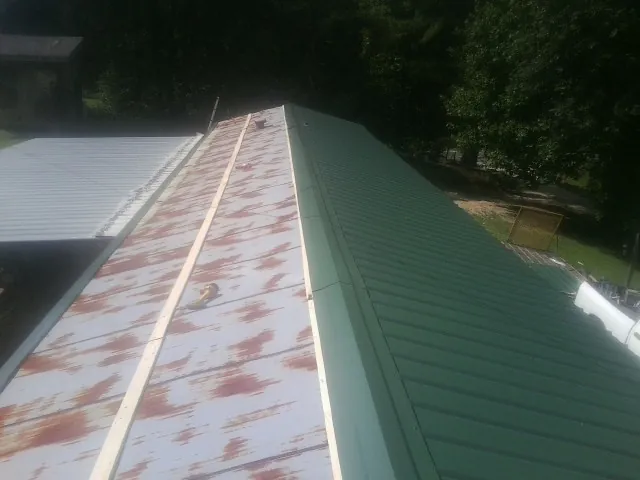 Old rusted panels beside newly installed green metal roofing — Wind Damage Roof Repair by Roofing Brothers in Colliersville
