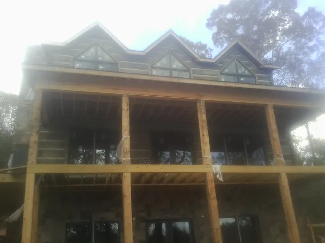 Dormers and porch framing on a large log home under construction — Roof Coating work by our crew in Colliersville