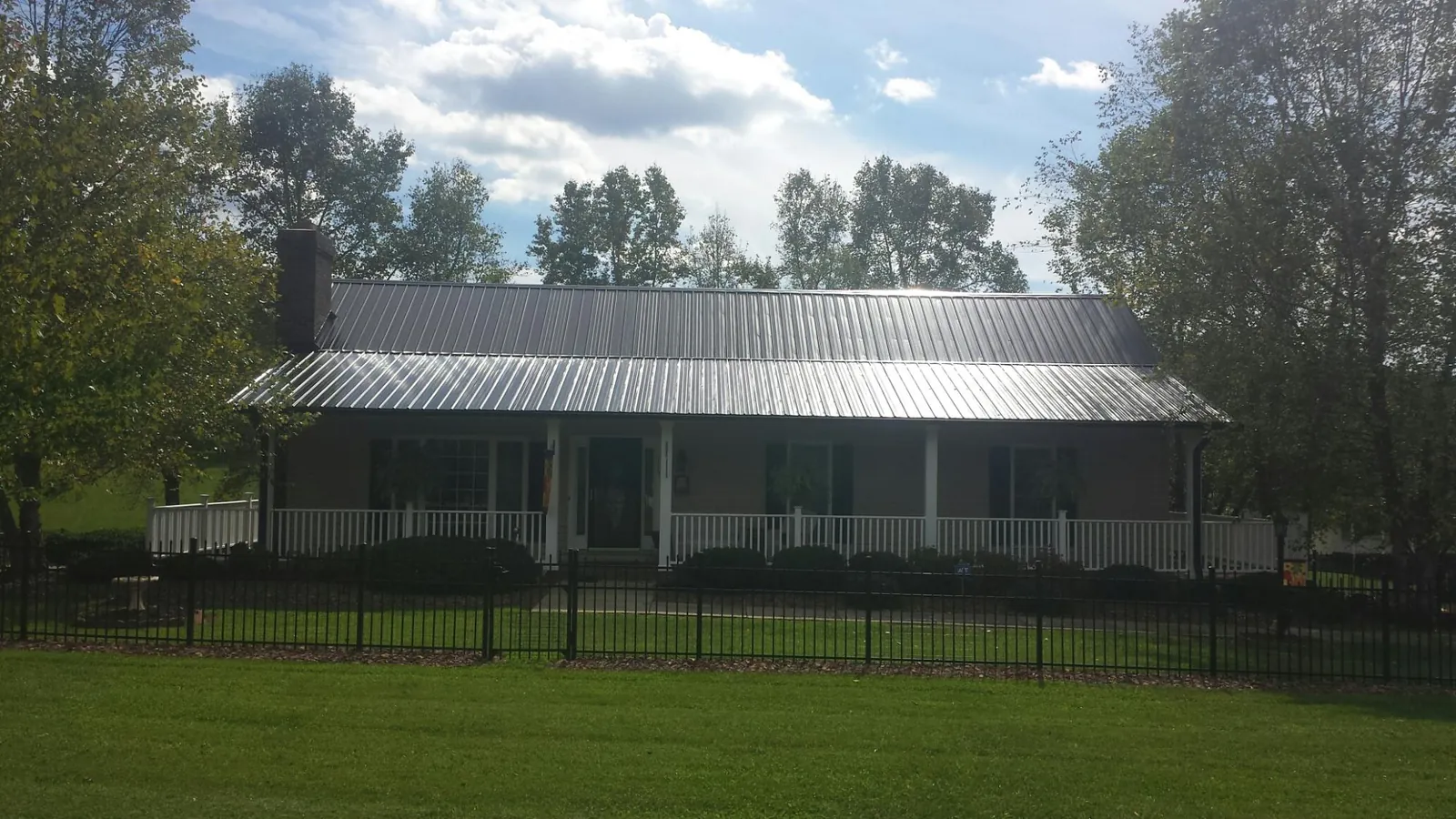 Gray metal roof on a brick ranch with a full width front porch — Gutter Guard Installation work by our crew in Colliersville