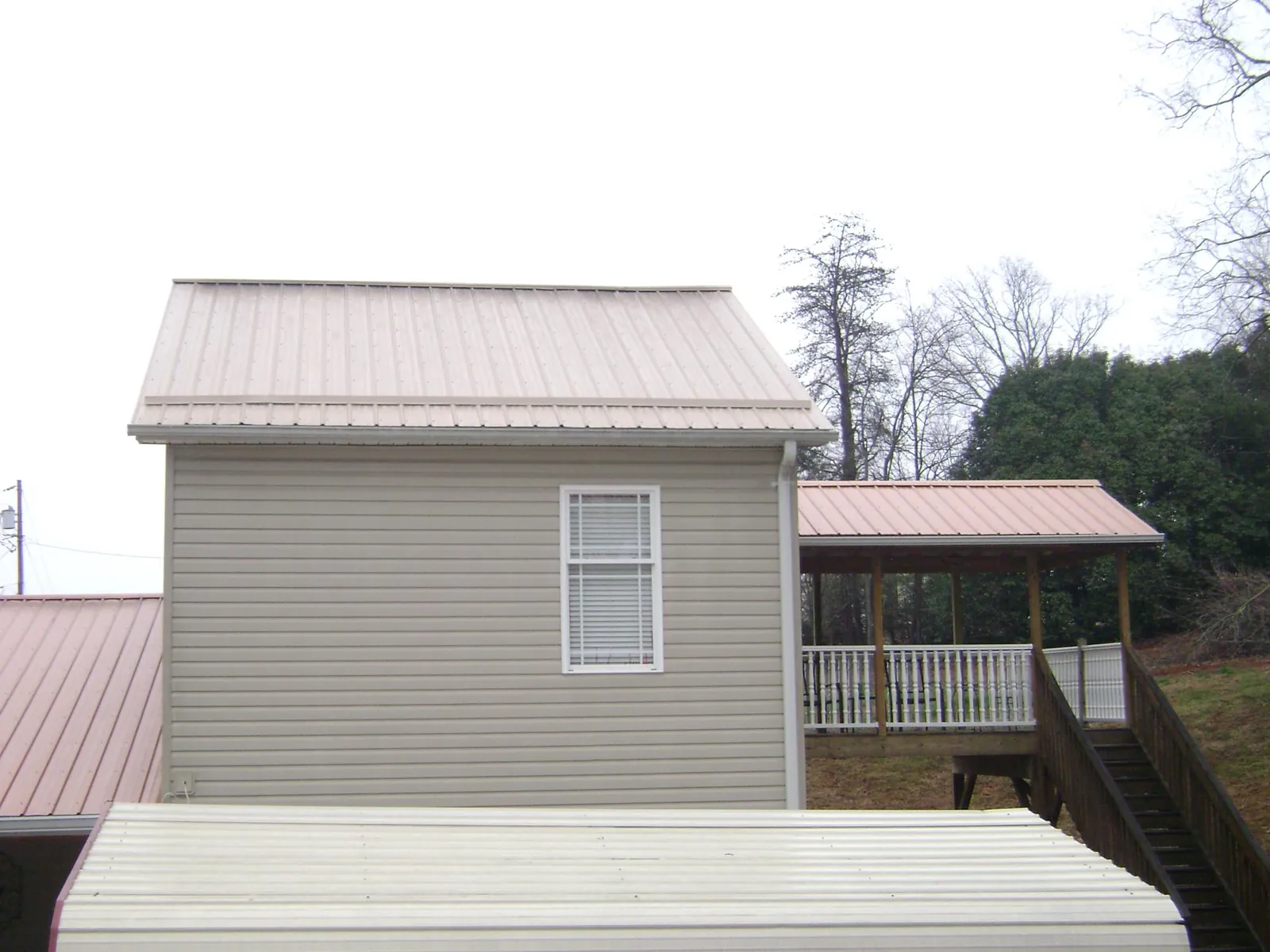 Tan metal roofs on a two story addition and attached porch, from a Roof Replacement job in Colliersville