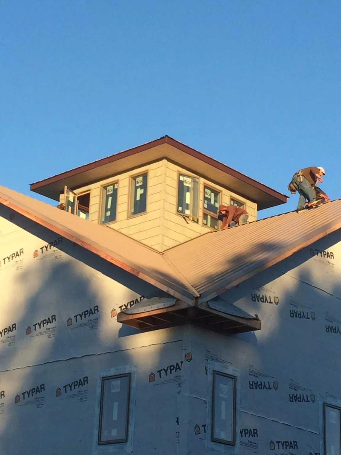 Roofers working around a rooftop cupola on a new metal roof at sunset — Roof Waterproofing in Colliersville by Roofing Brothers